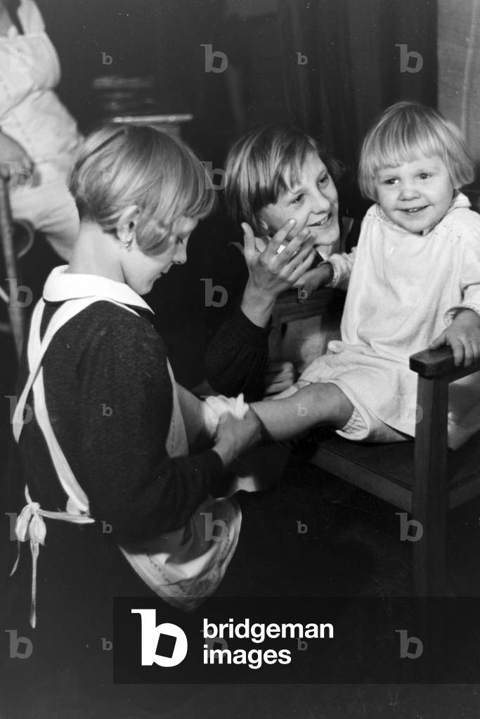 Two of the quadruplets of Brücken looking after their youngest sibling, Germany 1930s (b/w photo)