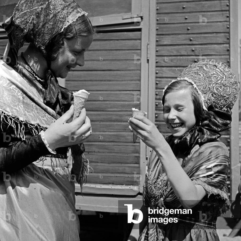 Two girls with an ice cream at a traditional costume parade through the streets of Constance, Germany 1930s (b/w photo)