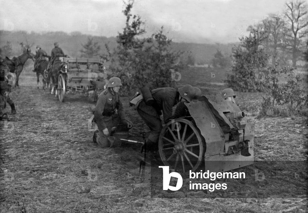 Infantry soldiers on a military training ground exercising with an infantry support gun, Germany 1930s (b/w photo)