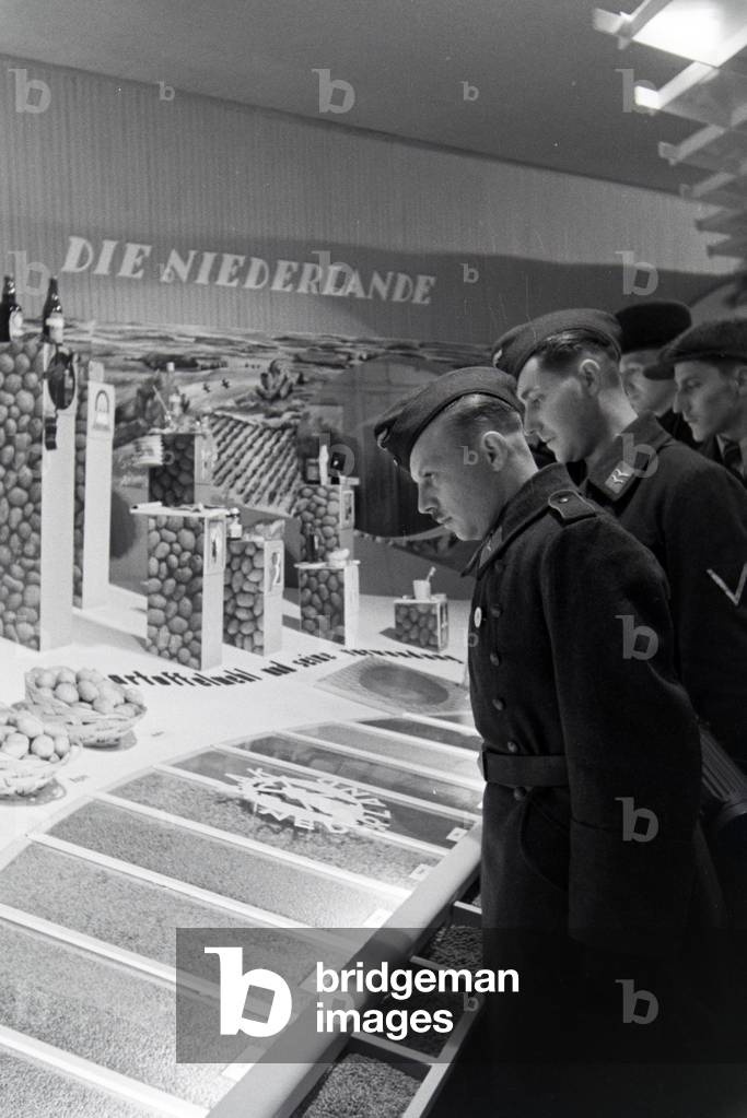 Soldiers at the Leipziger Frühjahrsmesse in front of a stand by the Netherlands with agricultural products, Germany 1941 (b/w photo)