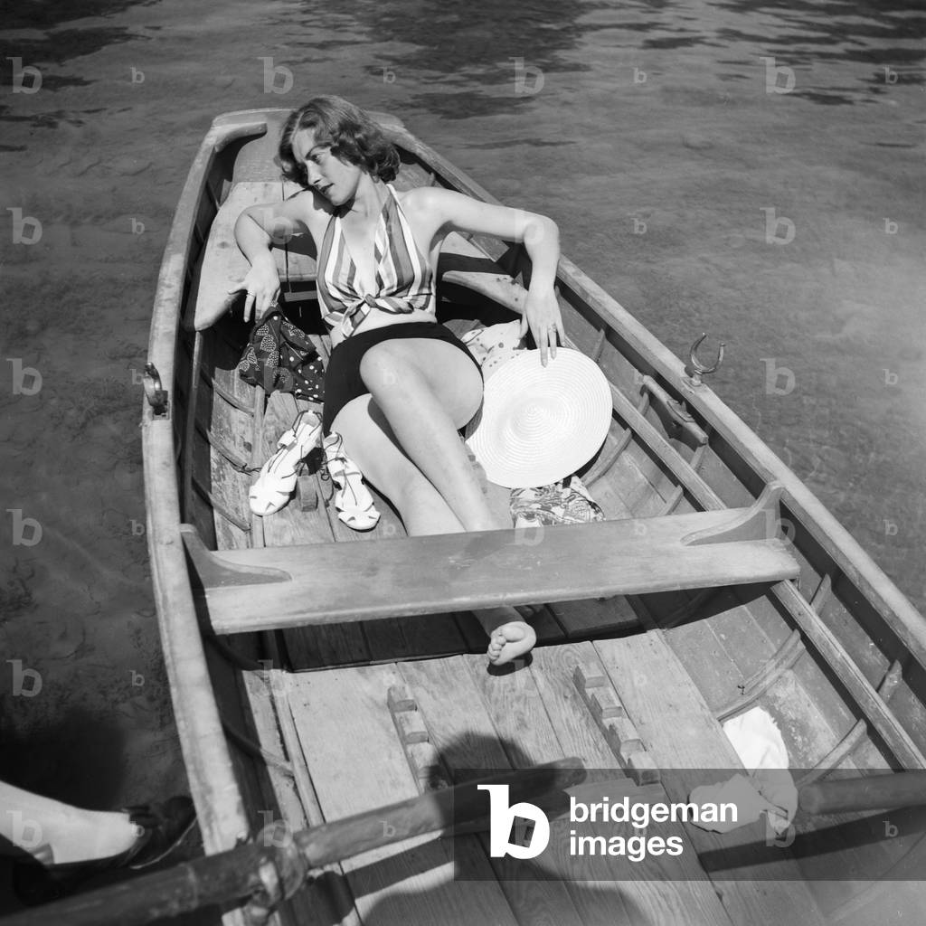 A young woman in a rowing boat on a lake in the Wachau area in Austria, Germany 1930s (b/w photo)