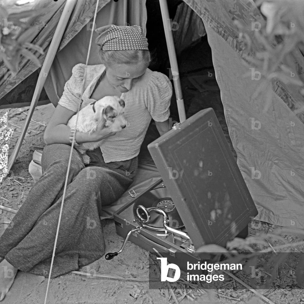 Advertising für a Klepper tent: a young woman sitting with a puppy in front of a tent, Germany 1930s (b/w photo)