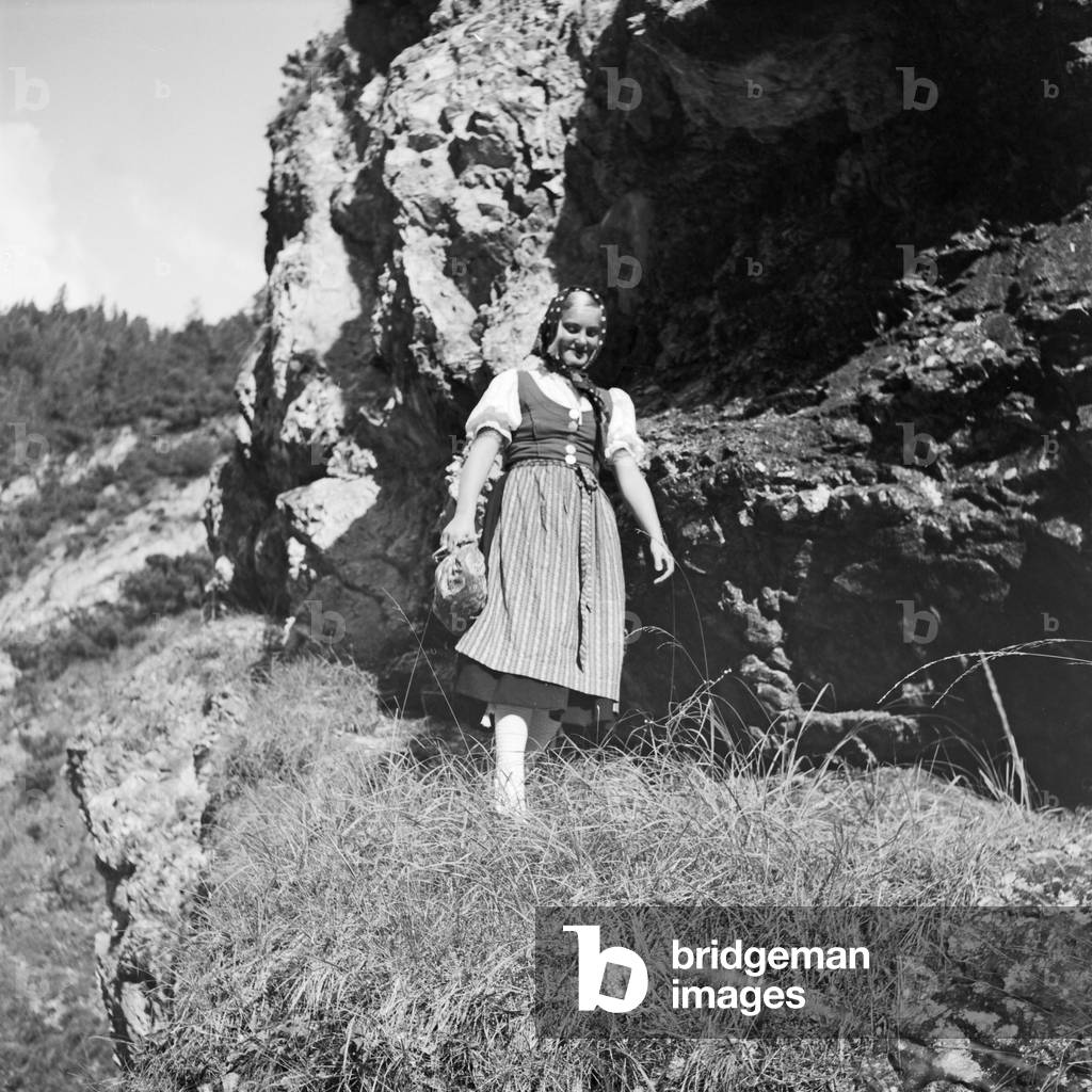 A young woman climbing on a mountain in the Wachau area in Austria, Germany 1930s (b/w photo)