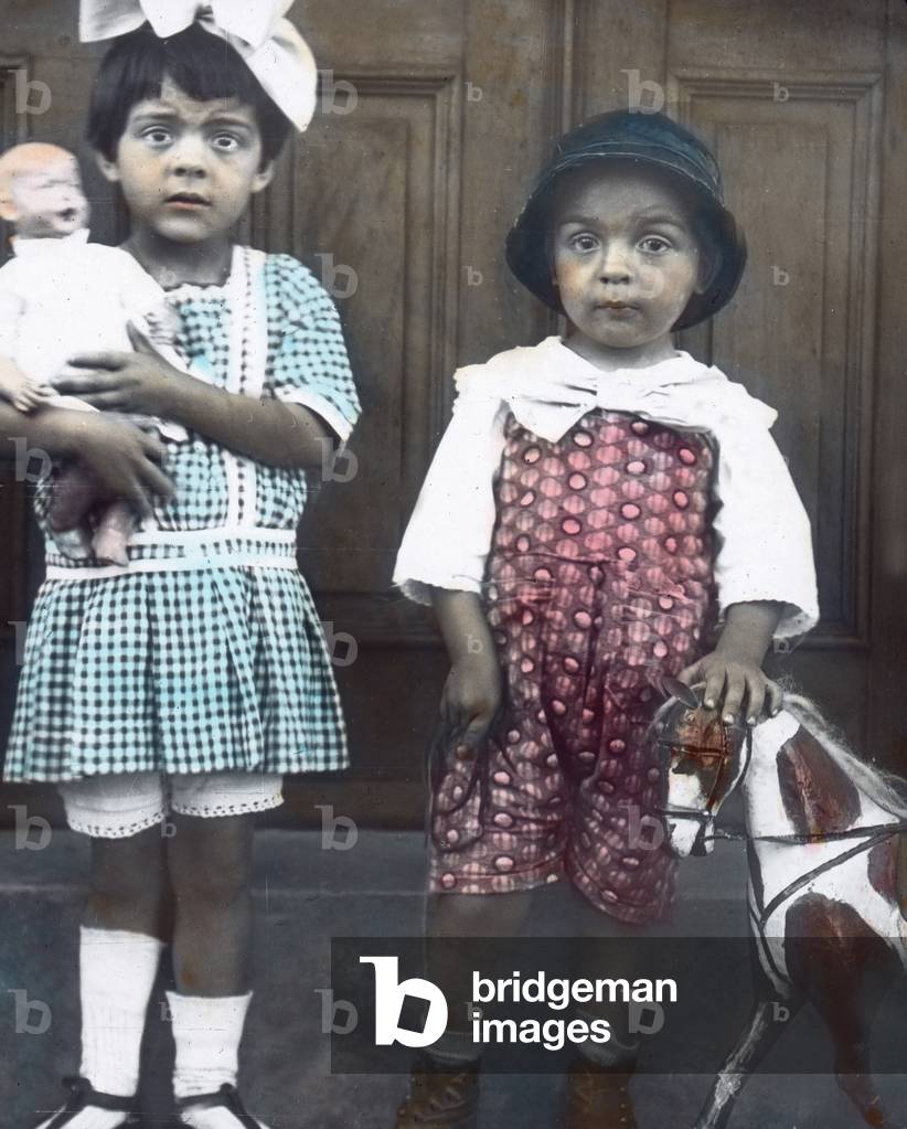 South America, Brazil. Children from Tubarao holding a doll and small wooden horse. Image date: circa 1930. Carl Simon Archive