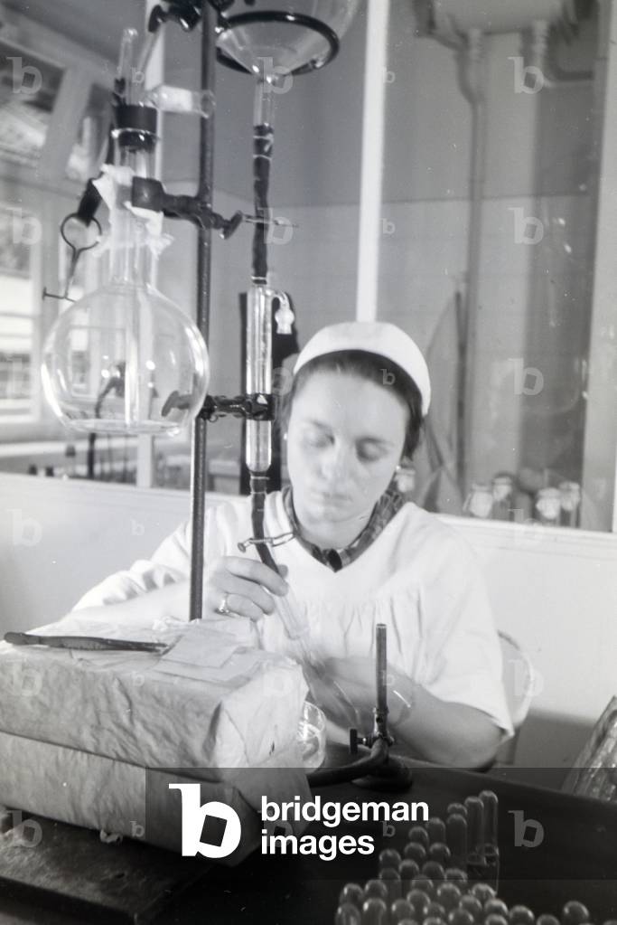A lab assistant is taking medication samples in the laboratory of the Behringwerke, Marburg, Germany 1930s (b/w photo)