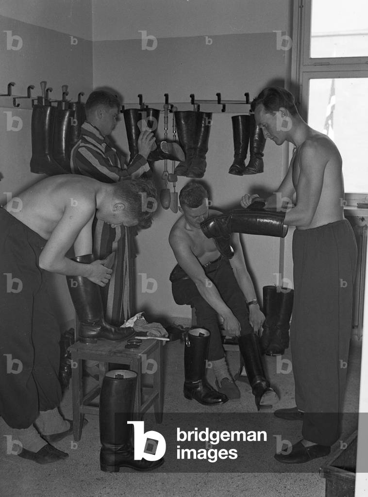 Young soldiers dressing up in their uniforms for duty, Germany 1930s (b/w photo)