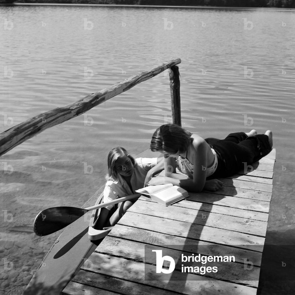 Two young women at the shore of a bathing lake in Austria, 1930s (b/w photo)