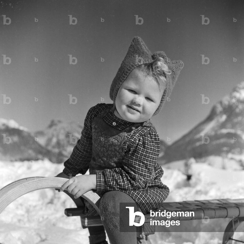 Little girl on her sleigh in winter time, Germany 1930s (b/w photo)