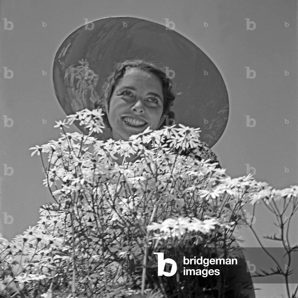 A young woman with a sun protection hat an a bunch of flowers, Germany 1930s (b/w photo)