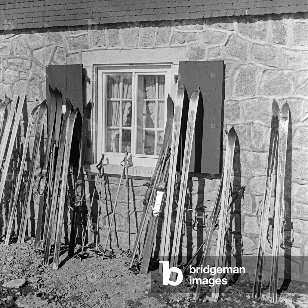 Skis standing at the wall of a ski hut, Germany 1930s (b/w photo)