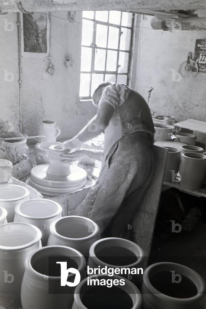 A master potter working on stoneware jars with the pottery wheel in the Kannenbäckerland, Germany 1930s (b/w photo)