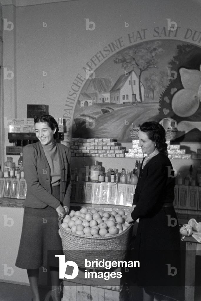 Employees of the Leipziger Frühjahrsmesse in front of a stand with spanish oranges, Germany 1941 (b/w photo)