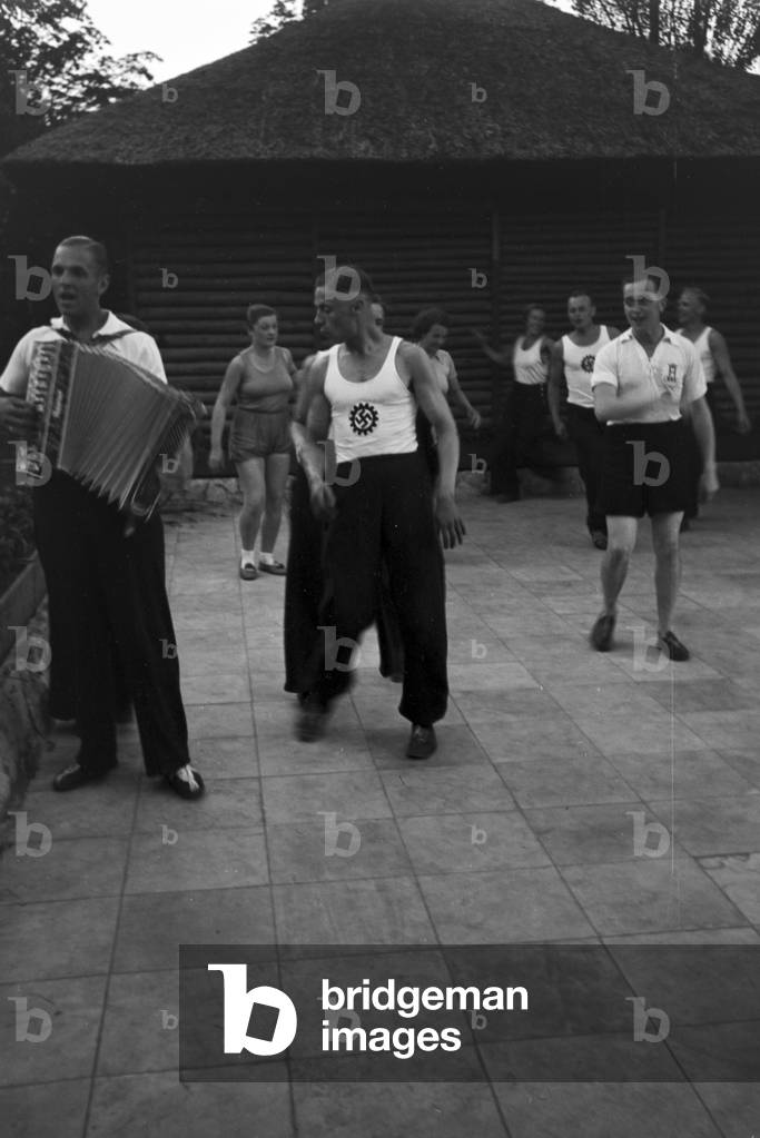 People dancing in front of forest huts at the sports club at Belzig in Brandenburg, Germany 1930s (b/w photo)