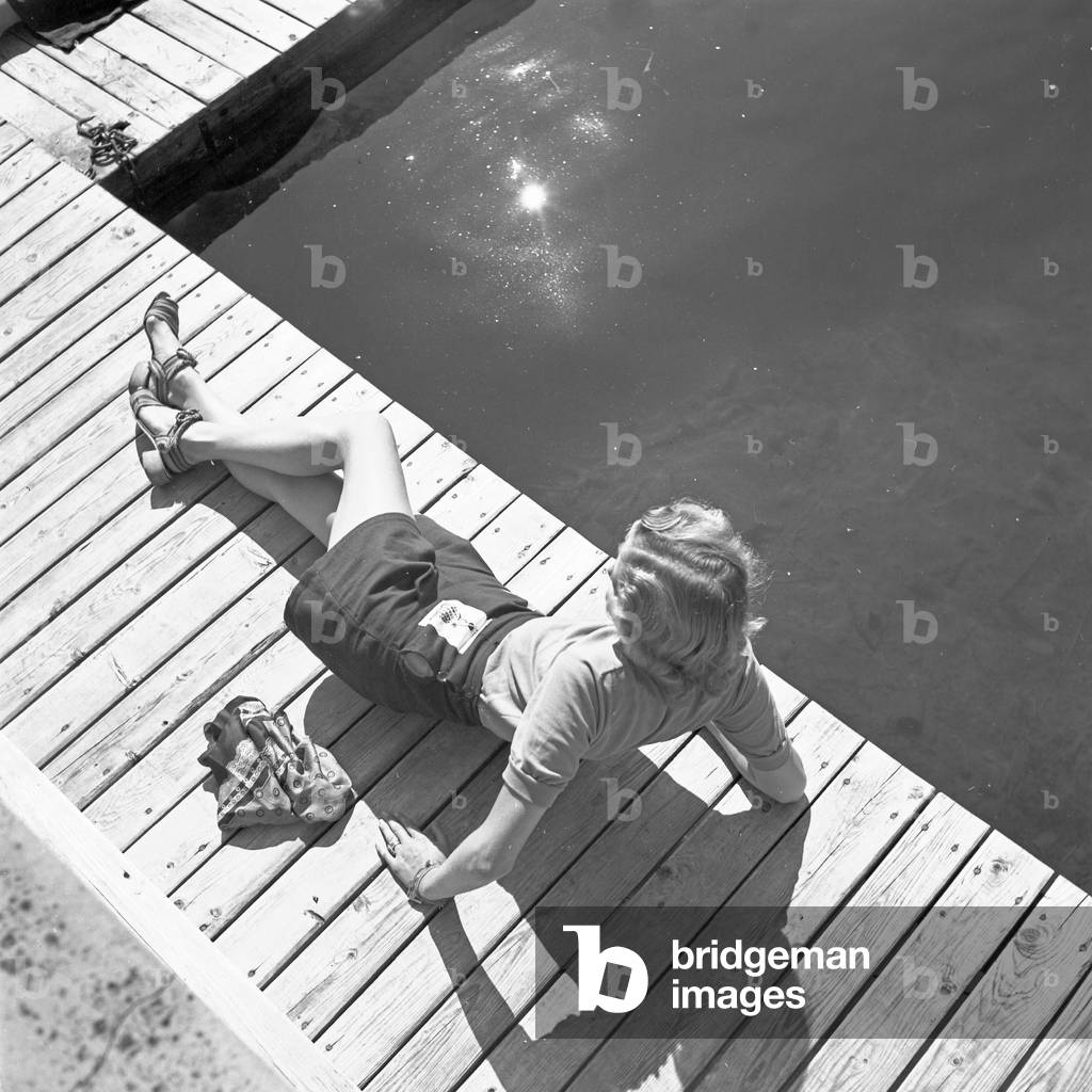 A young woman on a boardwalk on the shore of a lake in the Wachau area, Germany 1930s (b/w photo)