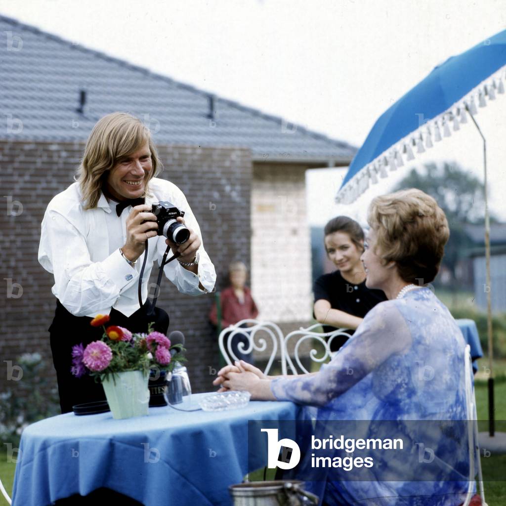 Actor Horst Janson taking a photo of German actress Lilli Palmer on the set of TV series 