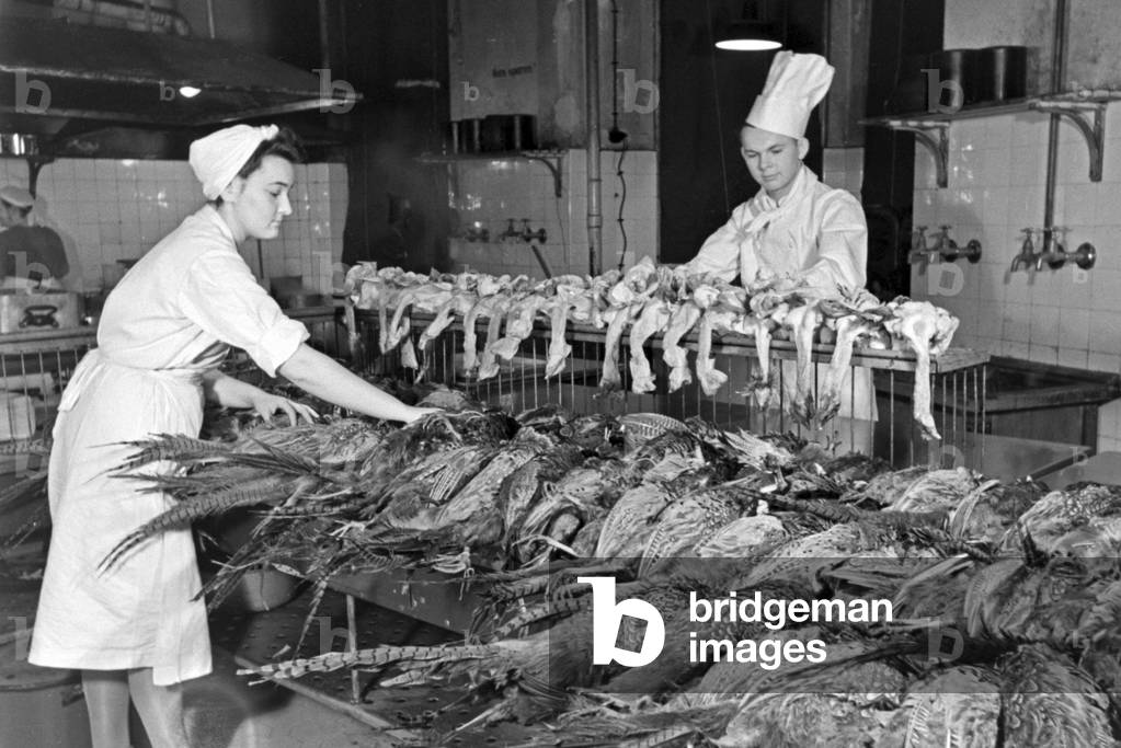 Two chefs with fresh poultry at the kitchen of a restaurant, Germany 1930s (b/w photo)