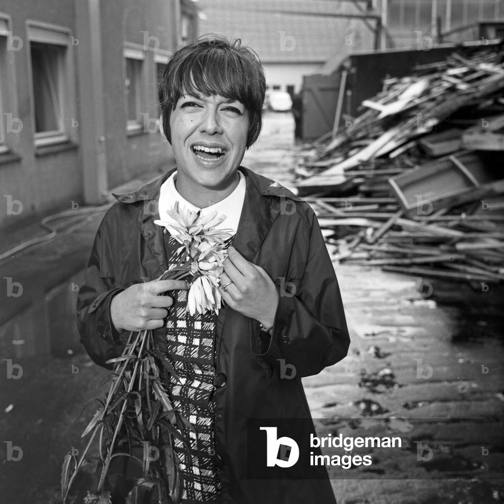A woman with flowers in a wet courtyard, Germany 1960s