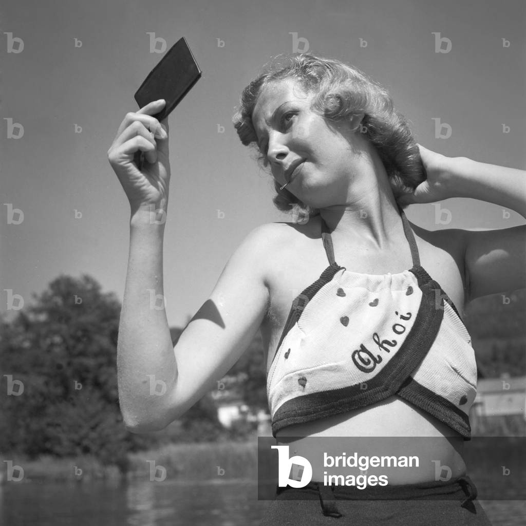 Young woman doing her hair at the beach of a lake in Austria, 1930s (b/w photo)