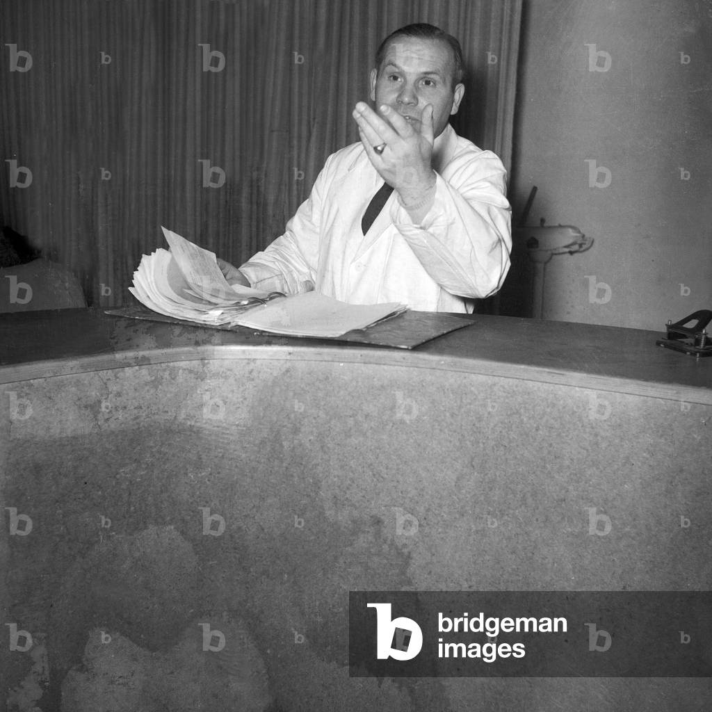 A man browsing in a file while standing at a marble counter, Germany 1954