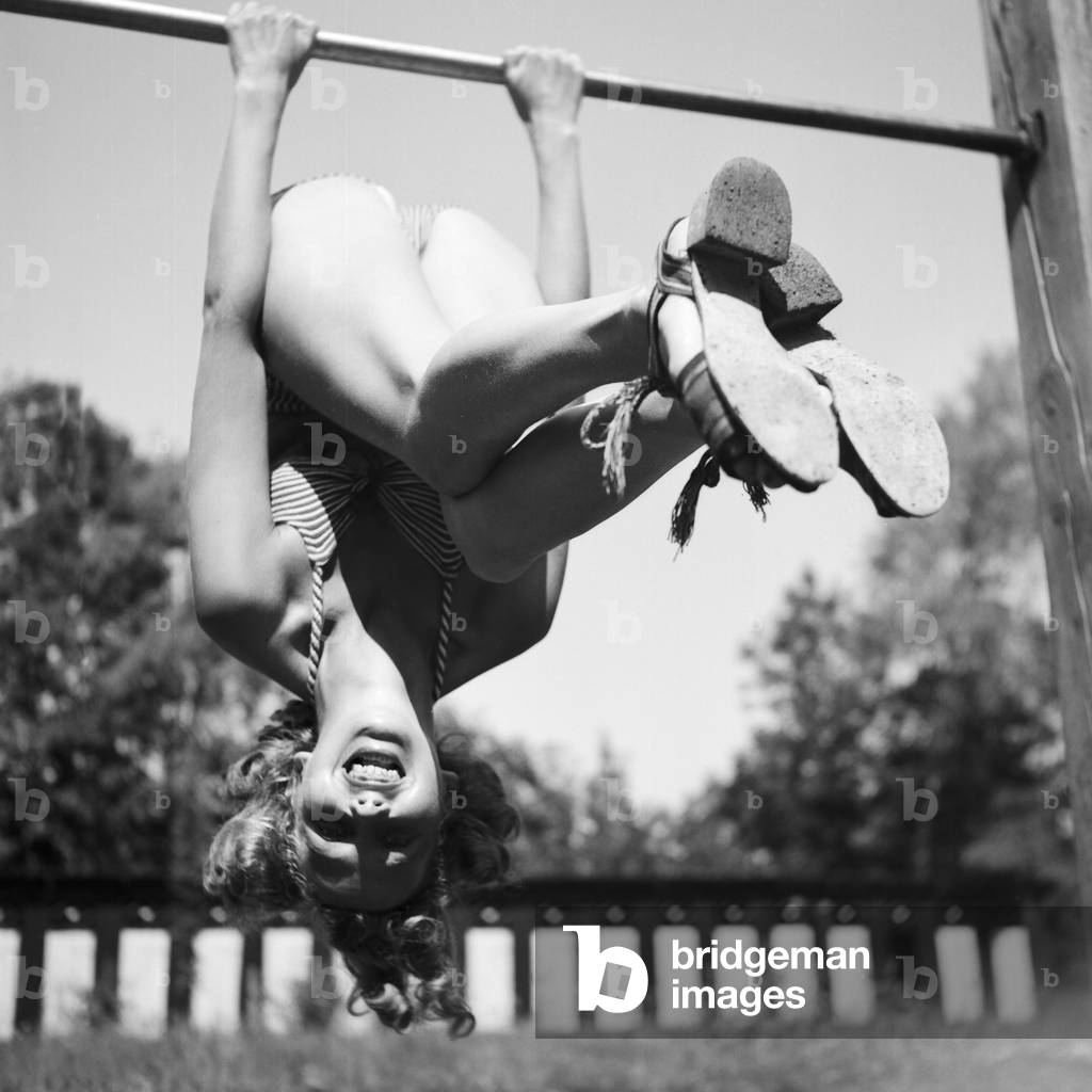 A young woman doing gymnastics on a playground in the Wachau area in Austria, Germany 1930s (b/w photo)