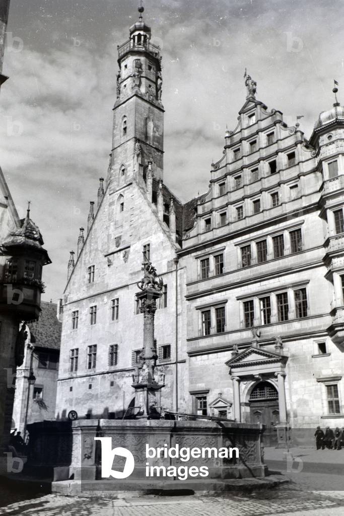 A fountain in front of the impressive town hall in Rothenburg ob der Tauber, Germany 1930s (b/w photo)