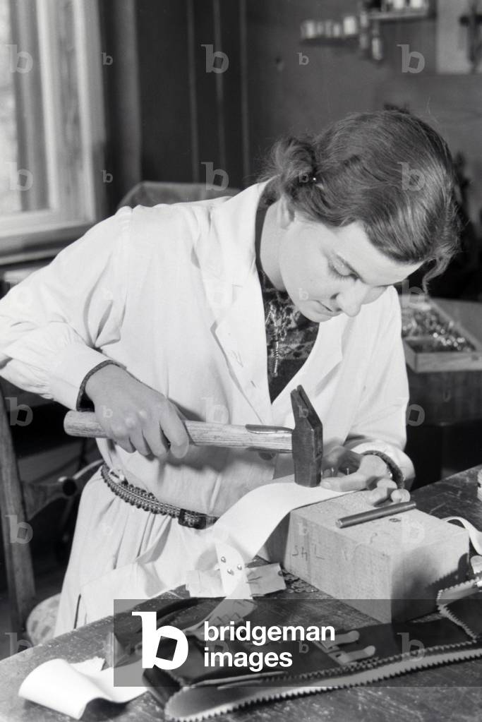 Woman punchinging different leather goods, Germany 1930s (b/w photo)