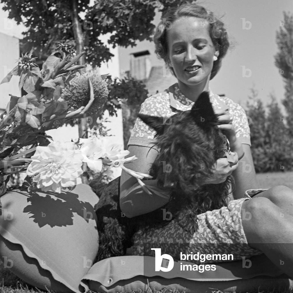 A young woman with her dog on a lawn, Germany 1930s (b/w photo)