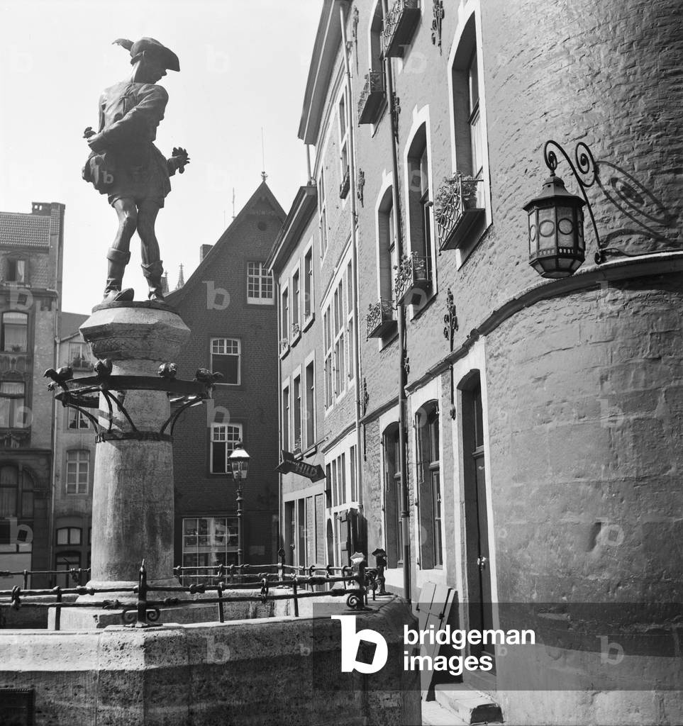 The Huehnerdieb fountain showing a chicken thief at Huehnermarkt square in Aachen, Germany 1930s (b/w photo)