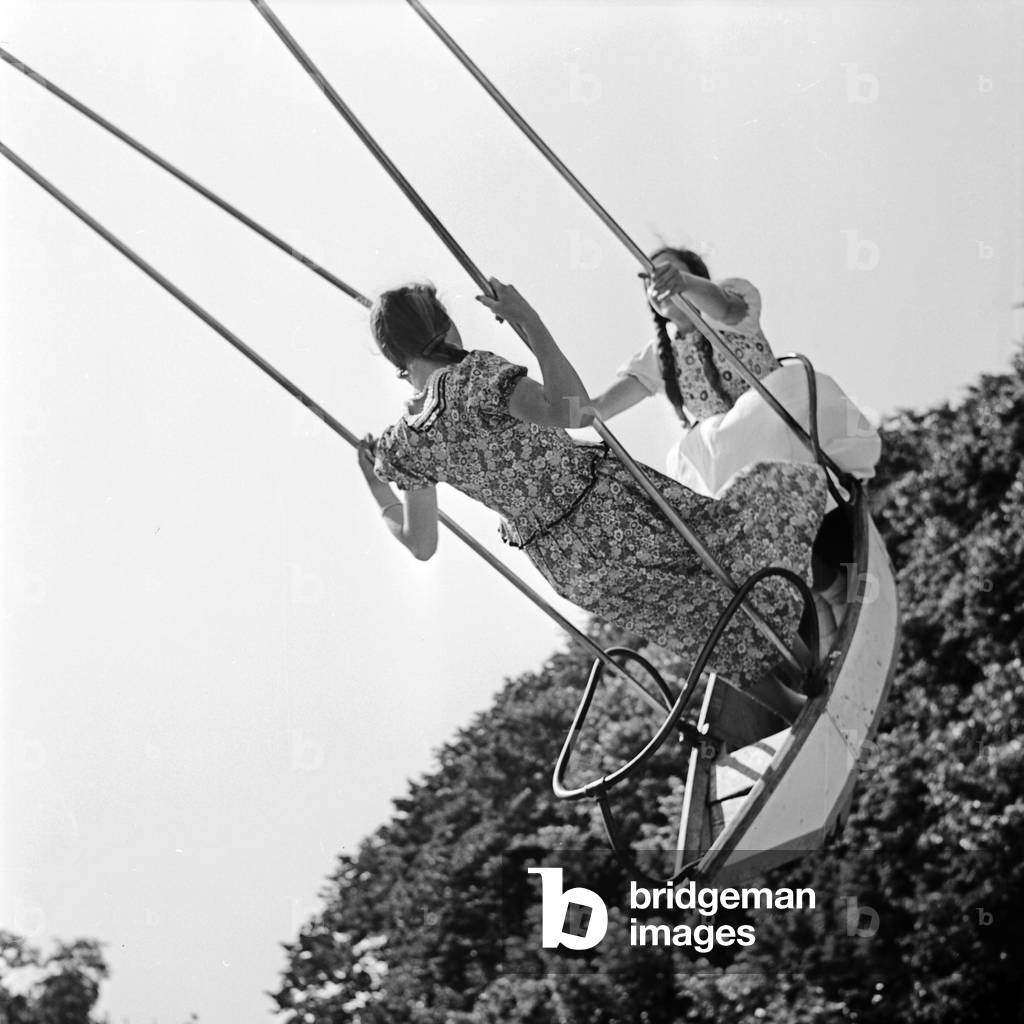 Two girls raving on a swingboat at an annual fair, Germany 1930s (b/w photo)