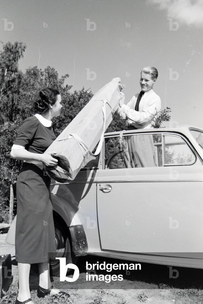 Young couple getting their luggage out of the car, Germany 1930s (b/w photo)