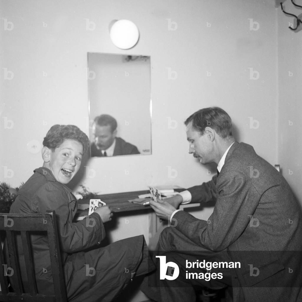 A little boy and a man sitting at a table, playing cards, Kiel, 1954