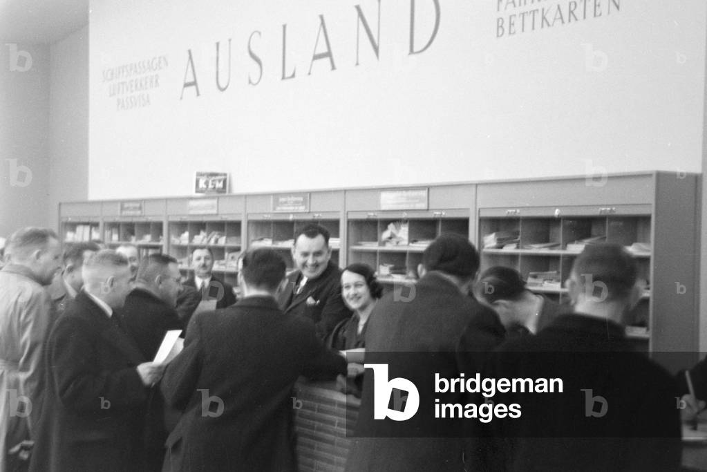 Travellers and staff members at a huge office of a travel agency in Berlin, Germany 1930s (b/w photo)