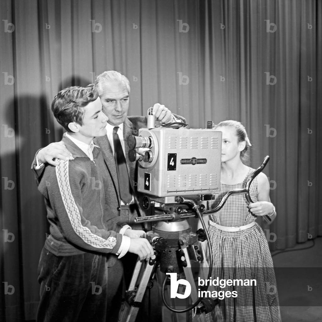 A camera man explaining how a TV camera work to a boy and a girl, Germany 1950s