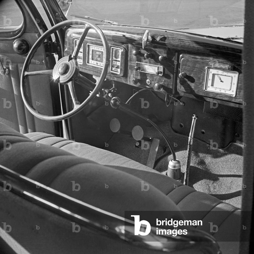 Driver's seat, steering wheel and car dashboard of a Ford V8, Germany 1930s (b/w photo)