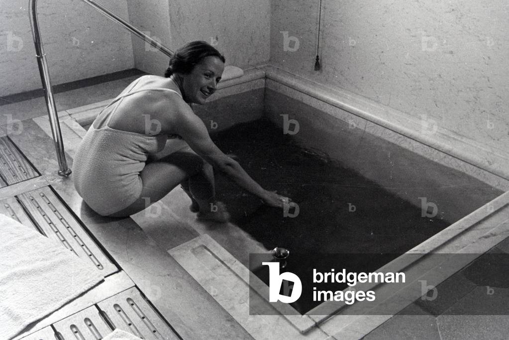 A young woman visiting the hot water pool in the Caracalla Therme in Baden-Baden, Germany 1930s (b/w photo)