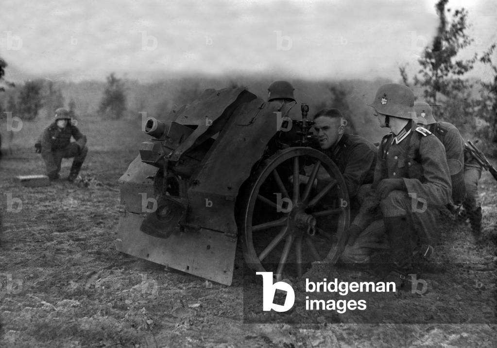 Infantry soldiers on a military training ground exercising with an infantry support gun, Germany 1930s (b/w photo)