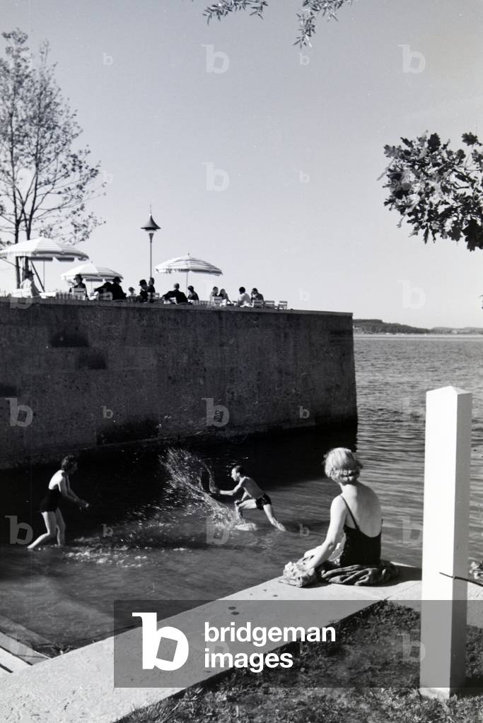 Two young women and a young man sunbathing and swimming in the Chiemsee, Dermany 1930s (b/w photo)