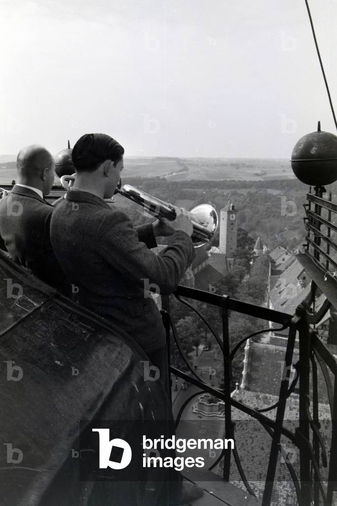 The sounds of the musicians trumpeting on the highest tower of the townhall are echoing over the whole city center of Rothenburg ob der Tauber, Germany 1930s (b/w photo)