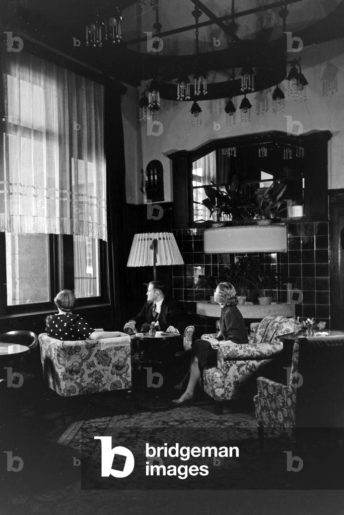 Guests sitting by the fireplace at Schlosshotel hotel at Oberhof in Thuringia, Germany 1930s (b/w photo)
