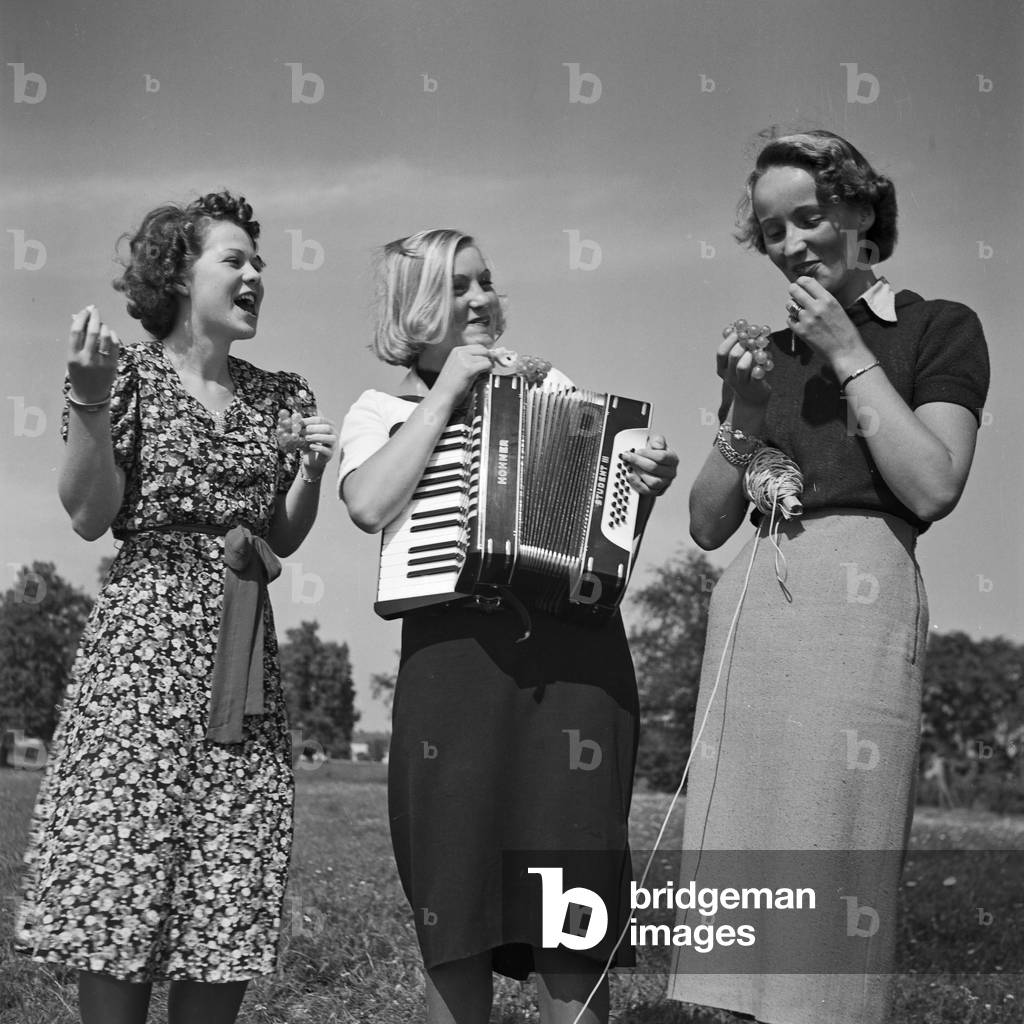 Three women playing music with an accordion, Germany 1930s (b/w photo)