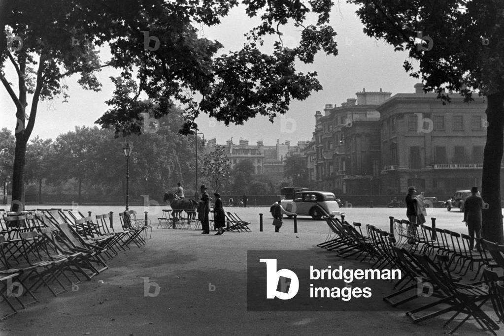 Passers by relaxing while watching the traffic at a city centre, Germany 1930s (b/w photo)