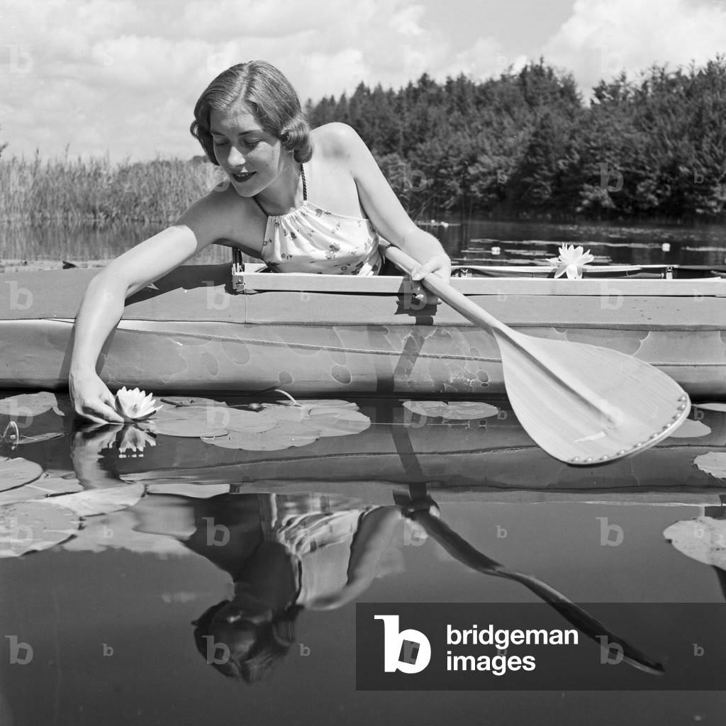 A young woman with her folding boat in the reed of a lake in the Wachau area, Germany 1930s (b/w photo)