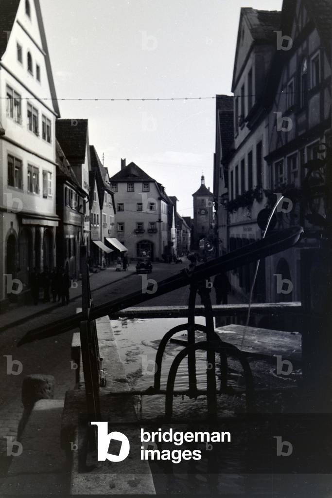 A street lined with half-timbered buildings and a fountain in Rothenburg ob der Tauber, Germany 1930s (b/w photo)