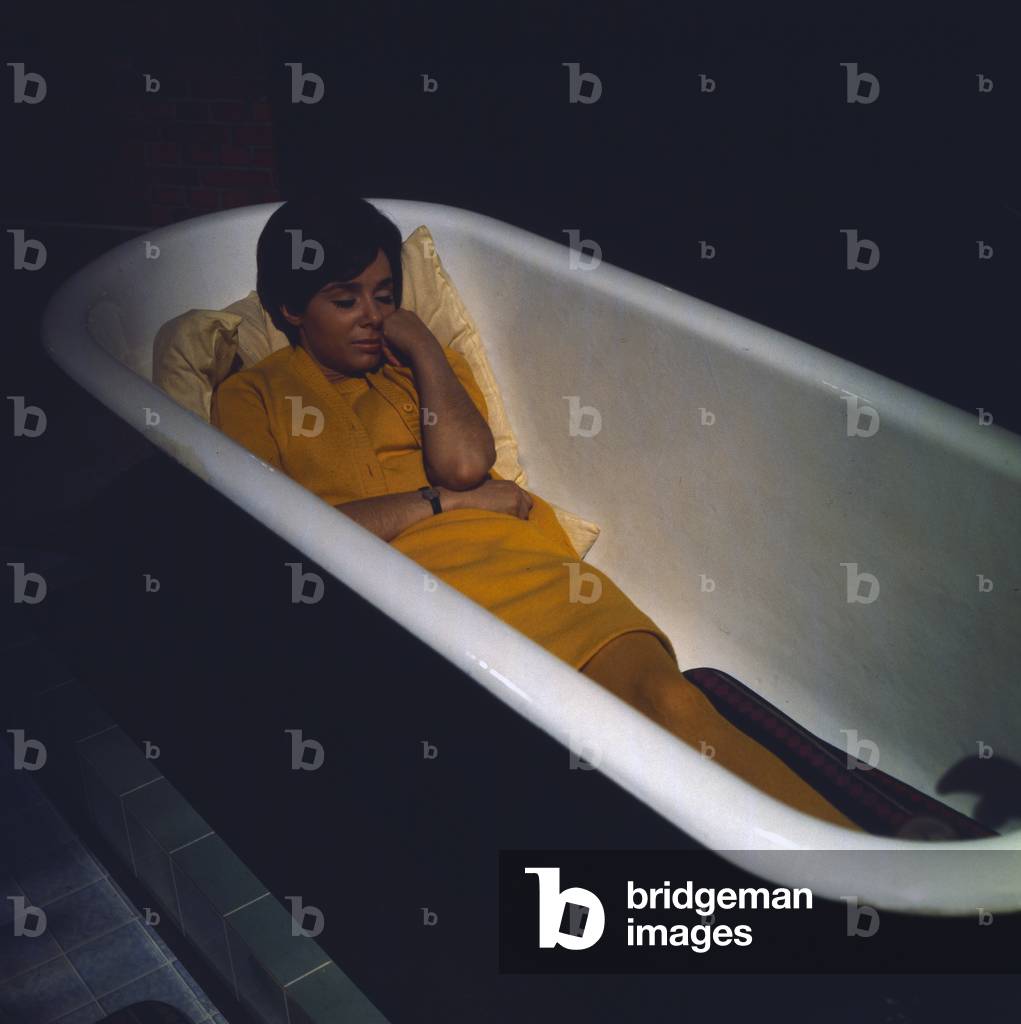 Actress Monika Peitsch taking a nap in a bath tub while a produciotn break