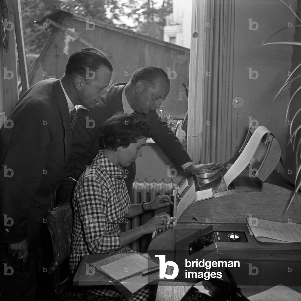 Kurt richter, CEO of record label Polydor, with staff members at the teletyper in the office at Hamburg, Germany 1950s