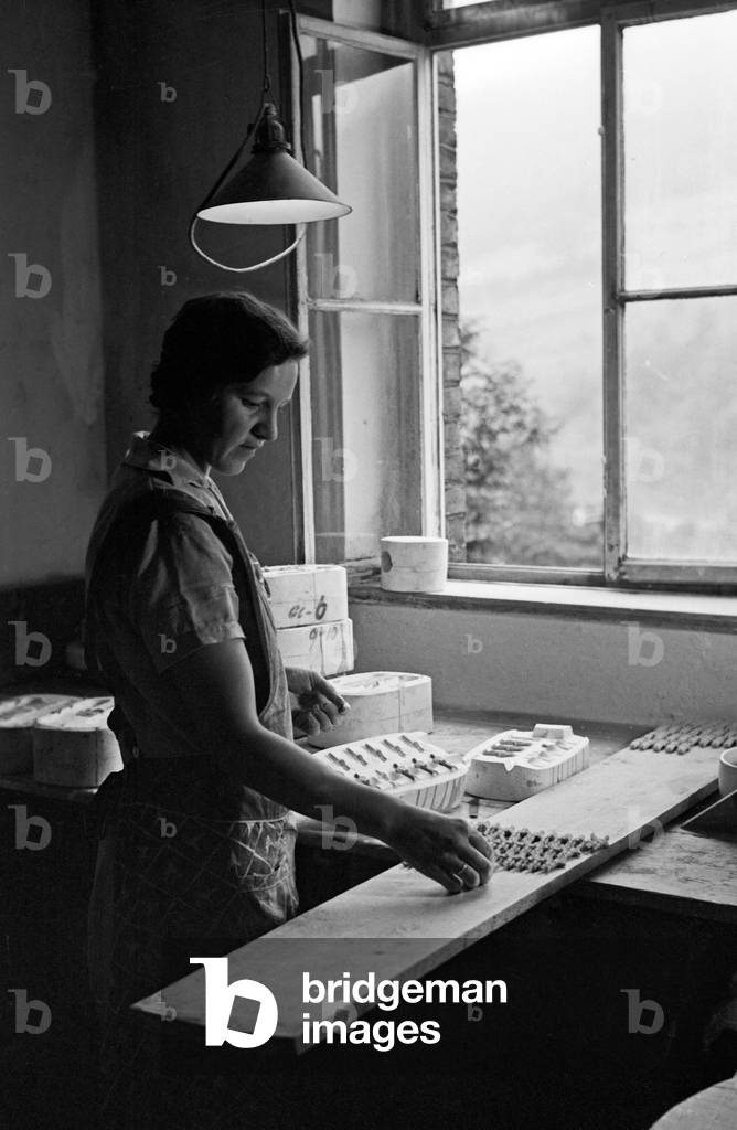 A female worker of the porcellain factory at Graefenthal, Thuringia, pouring porcellain raw mixture into a mold, Germany 1930s (b/w photo)