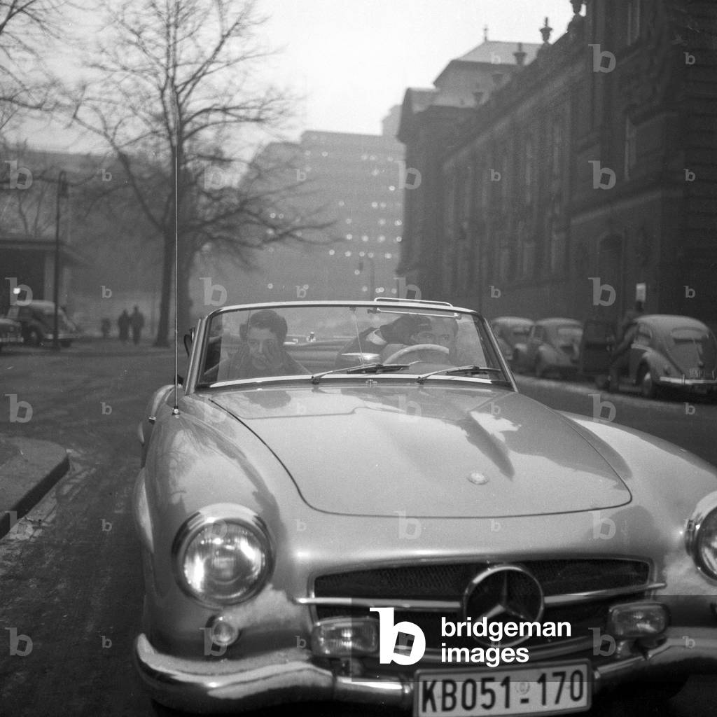 A couple driving throug hHamburg city centre in their Mercedes Benz convertible, 1955