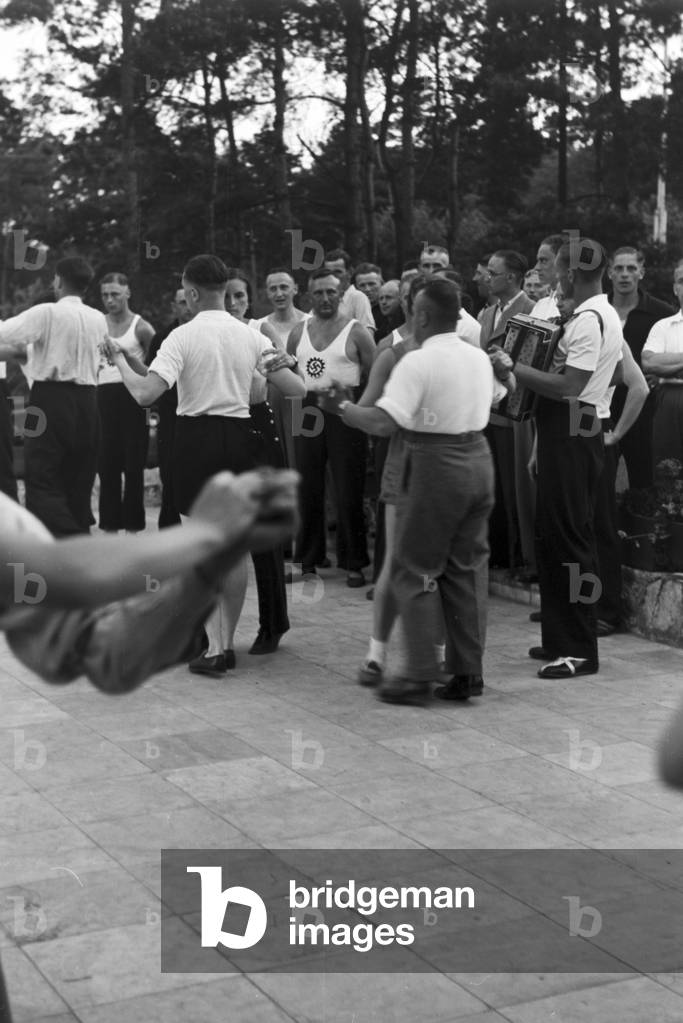 People singing and dancing in front of forest huts at the sports club at Belzig in Brandenburg, Germany 1930s (b/w photo)