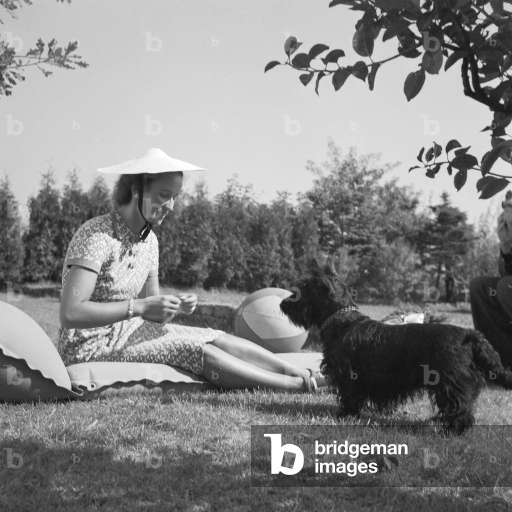 A young woman with her dog on a lawn, Germany 1930s (b/w photo)