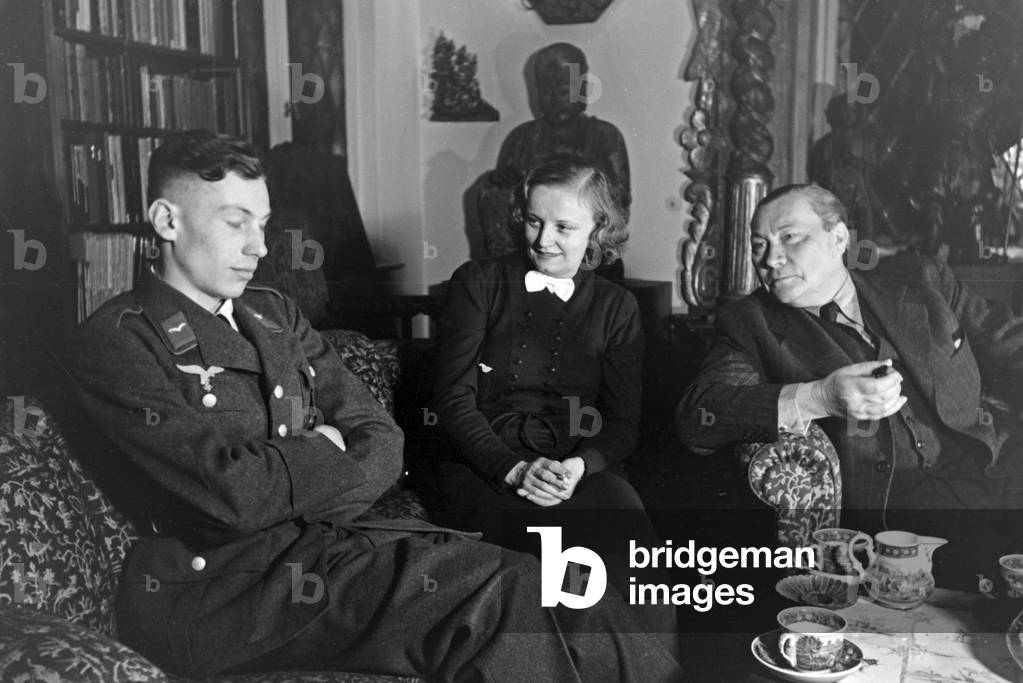 German actor Paul Wegener smoking a cigar while sitting in his living room with his wife, actress Greta Schroeder and his son Peter, at his house in Berlin, Germany 1930s (b/w photo)
